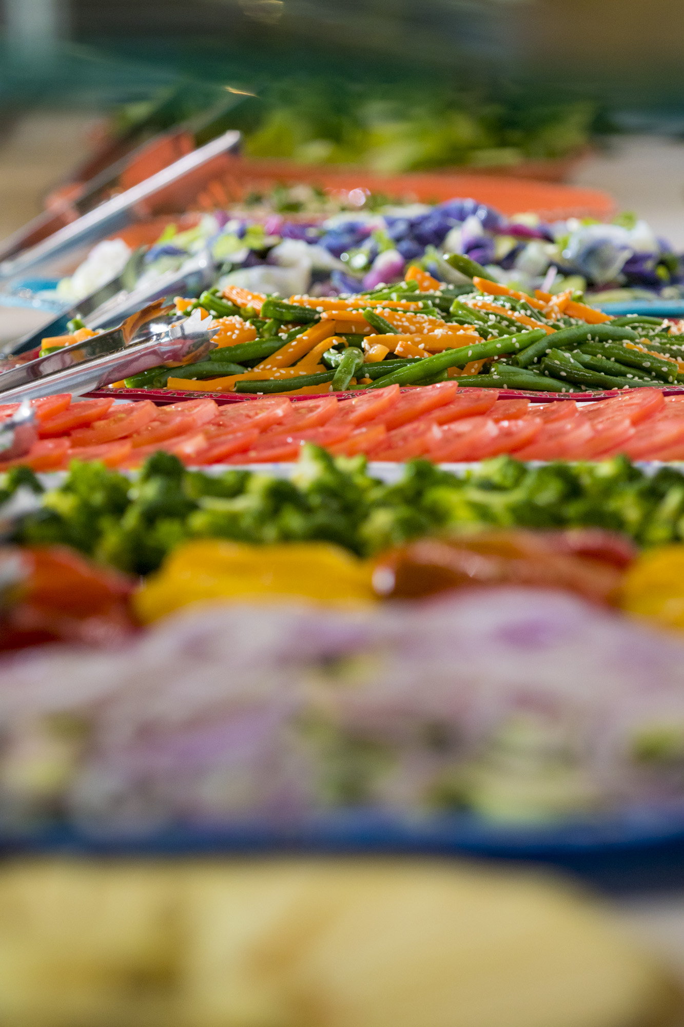 Colorful grilled vegetables and meats arranged on a platter at a Brazilian steakhouse, including green beans, red peppers, and various cuts of churrasco.